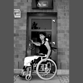 Foto von einer Rollstuhlfahrerin vor einer handbetriebenen T�r